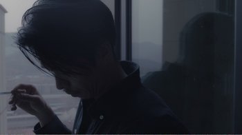 Movie still from “An Elephant Sitting Still” (2018), directed by Bo Hu – A man looking at his cell phone while standing in front of a window; Close Up shot, Low angle