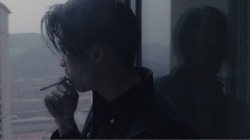 Movie still from “An Elephant Sitting Still” (2018), directed by Bo Hu – A man is looking out a window at the street; Close Up shot, Over the shoulder angle