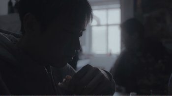 Movie still from “An Elephant Sitting Still” (2018), directed by Bo Hu – A person sitting in front of a window eating a piece of food; Extreme Close Up shot, Over the shoulder angle