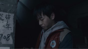 Movie still from “An Elephant Sitting Still” (2018), directed by Bo Hu – A young man is looking down at his cell phone; Close Up shot, Overhead angle