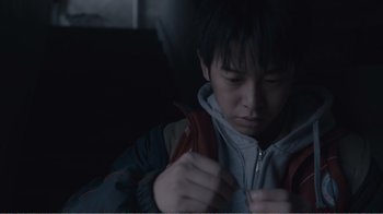 Movie still from “An Elephant Sitting Still” (2018), directed by Bo Hu – A young man holding a pair of scissors in his hands; Close Up shot, Low angle