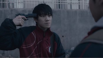 Movie still from “An Elephant Sitting Still” (2018), directed by Bo Hu – A young man holding a gun in his hand; Close Up shot, High angle