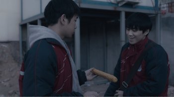 Movie still from “An Elephant Sitting Still” (2018), directed by Bo Hu – Two young men are holding a hot dog in their hands; Medium shot, Over the shoulder angle