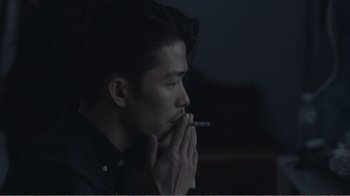 Movie still from “An Elephant Sitting Still” (2018), directed by Bo Hu – A man is smoking a cigarette in a dark room; Close Up shot, Over the shoulder angle