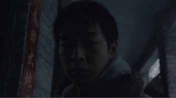 Movie still from “An Elephant Sitting Still” (2018), directed by Bo Hu – A young boy is looking at the camera; Close Up shot, Low angle