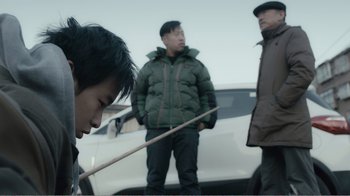 Movie still from “An Elephant Sitting Still” (2018), directed by Bo Hu – A group of men standing next to each other near a white car; Medium shot, Over the shoulder angle