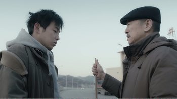 Movie still from “An Elephant Sitting Still” (2018), directed by Bo Hu – Two men standing next to each other on a street; Medium shot, Over the shoulder angle