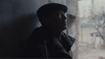 Movie still from “An Elephant Sitting Still” (2018), directed by Bo Hu – A man wearing a hat looking up at the sky; Close Up shot, Low angle