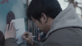 Movie still from “An Elephant Sitting Still” (2018), directed by Bo Hu – A man writing on a piece of paper with a pencil; Extreme Close Up shot, Over the shoulder angle