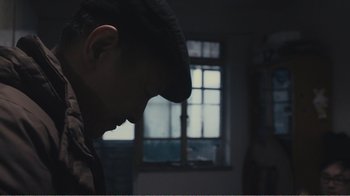 Movie still from “An Elephant Sitting Still” (2018), directed by Bo Hu – A man with his head down in a dark room; Close Up shot, Low angle
