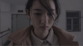 Movie still from “An Elephant Sitting Still” (2018), directed by Bo Hu – A woman with long black hair wearing a white shirt; Close Up shot, High angle