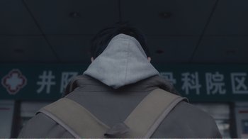 Movie still from “An Elephant Sitting Still” (2018), directed by Bo Hu – A man with a hood on his head; Extreme Close Up shot, Low angle