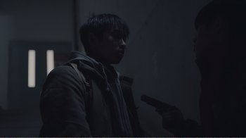 Movie still from “An Elephant Sitting Still” (2018), directed by Bo Hu – A man holding a gun in a dark room; Close Up shot, Over the shoulder angle