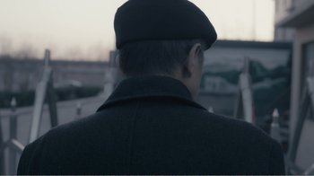 Movie still from “An Elephant Sitting Still” (2018), directed by Bo Hu – A man wearing a black hat and a black coat; Close Up shot, Over the shoulder angle
