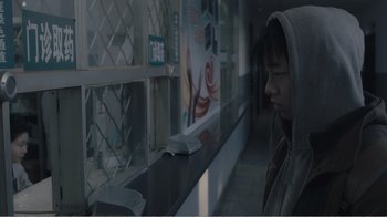Movie still from “An Elephant Sitting Still” (2018), directed by Bo Hu – A person standing in front of a counter; Close Up shot, Over the shoulder angle