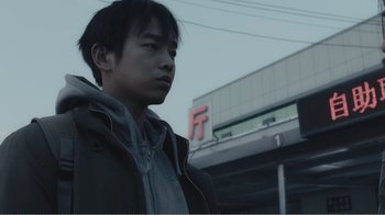 Movie still from “An Elephant Sitting Still” (2018), directed by Bo Hu – A young man standing in front of a building; Close Up shot, Low angle