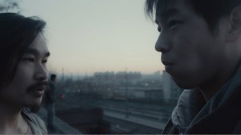 Movie still from “An Elephant Sitting Still” (2018), directed by Bo Hu – A young man looking out a window at a city; Close Up shot, Low angle