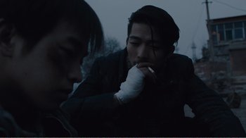 Movie still from “An Elephant Sitting Still” (2018), directed by Bo Hu – A man smoking a cigarette while another man holds a cigarette; Close Up shot, Over the shoulder angle
