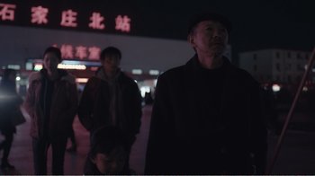 Movie still from “An Elephant Sitting Still” (2018), directed by Bo Hu – A group of people standing on a sidewalk at night; Medium shot, Low angle