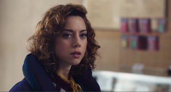 Movie still from “An Evening with Beverly Luff Linn” (2018), directed by Jim Hosking – A person with curly hair wearing a necklace; Close Up shot, Over the shoulder angle