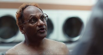 Movie still from “An Evening with Beverly Luff Linn” (2018), directed by Jim Hosking – A man with glasses is looking at the camera; Close Up shot, Over the shoulder angle