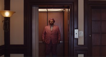 Movie still from “An Evening with Beverly Luff Linn” (2018), directed by Jim Hosking – A man in a suit and tie standing in an elevator; Wide shot, Low angle