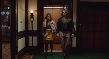 Movie still from “An Evening with Beverly Luff Linn” (2018), directed by Jim Hosking – A man and a woman are walking in a hallway; Wide shot, Low angle