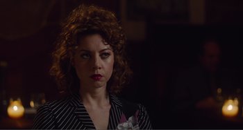 Movie still from “An Evening with Beverly Luff Linn” (2018), directed by Jim Hosking – A woman with curly red hair wearing a black and white striped suit; Close Up shot, Over the shoulder angle