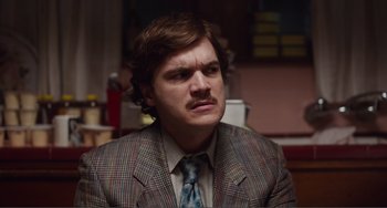 Movie still from “An Evening with Beverly Luff Linn” (2018), directed by Jim Hosking – A man in a suit and tie with a mustache; Close Up shot, Over the shoulder angle
