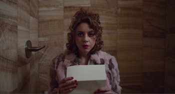 Movie still from “An Evening with Beverly Luff Linn” (2018), directed by Jim Hosking – A woman holding a piece of paper in her hands; Medium shot, High angle
