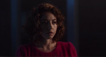 Movie still from “An Evening with Beverly Luff Linn” (2018), directed by Jim Hosking – A person with curly hair wearing a red shirt; Close Up shot, Over the shoulder angle