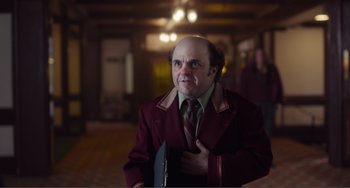 Movie still from “An Evening with Beverly Luff Linn” (2018), directed by Jim Hosking – A bald man in a red jacket and a brown tie; Medium shot, Over the shoulder angle