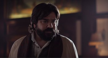 Movie still from “An Evening with Beverly Luff Linn” (2018), directed by Jim Hosking – A man with long hair and a beard looking to his left; Close Up shot, Over the shoulder angle