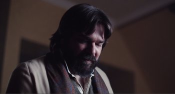 Movie still from “An Evening with Beverly Luff Linn” (2018), directed by Jim Hosking – A man with long hair and a beard looking to his left; Close Up shot, Over the shoulder angle