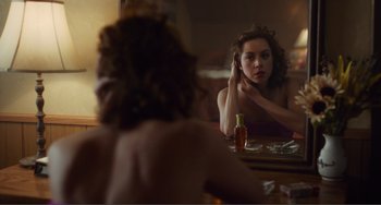 Movie still from “An Evening with Beverly Luff Linn” (2018), directed by Jim Hosking – A woman sitting in front of a mirror looking at herself in the mirror; Medium shot, Over the shoulder angle