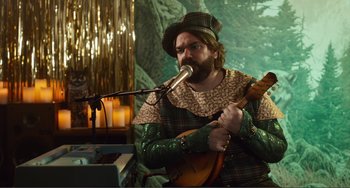 Movie still from “An Evening with Beverly Luff Linn” (2018), directed by Jim Hosking – A man with a beard is holding a guitar; Medium shot, Over the shoulder angle