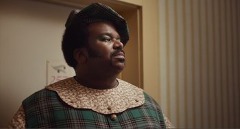 Movie still from “An Evening with Beverly Luff Linn” (2018), directed by Jim Hosking – A man in a green and white outfit with a hat; Close Up shot, Over the shoulder angle