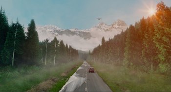 Movie still from “An Evening with Beverly Luff Linn” (2018), directed by Jim Hosking – A car driving down a road in the middle of a forest; Extreme Wide shot, High angle