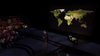 Movie still from “An Inconvenient Truth” (2006), directed by Davis Guggenheim – A man standing in front of a projection of a world map; Extreme Wide shot, High angle