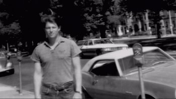 Movie still from “An Inconvenient Truth” (2006), directed by Davis Guggenheim – A black and white photo of a man standing in a parking lot; Medium shot, Low angle
