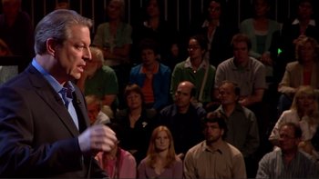 Movie still from “An Inconvenient Truth” (2006), directed by Davis Guggenheim – A crowd of people sitting and standing in front of a speaker; Close Up shot, Over the shoulder angle