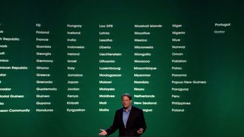 Movie still from “An Inconvenient Truth” (2006), directed by Davis Guggenheim – A man standing in front of a green wall with many languages written on it; Wide shot, High angle