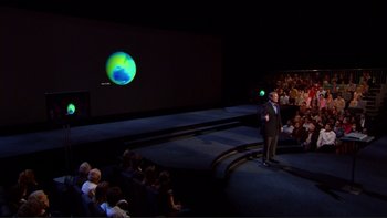 Movie still from “An Inconvenient Truth” (2006), directed by Davis Guggenheim – A man standing in front of an audience in front of a projection screen; Extreme Wide shot, High angle