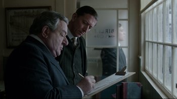 Movie still from “An Inspector Calls” (2015), directed by Raymond Pak-Ming Wong – Two men in suits are looking at papers; Medium shot, Over the shoulder angle