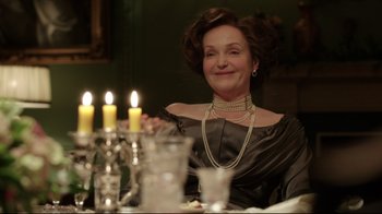 Movie still from “An Inspector Calls” (2015), directed by Raymond Pak-Ming Wong – An older woman sitting at a dinner table with candles; Medium shot, Over the shoulder angle