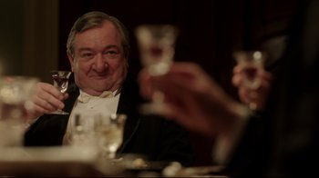 Movie still from “An Inspector Calls” (2015), directed by Raymond Pak-Ming Wong – A man sitting at a dinner table with a glass of wine in front of him; Close Up shot, Over the shoulder angle