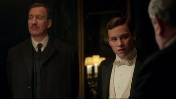 Movie still from “An Inspector Calls” (2015), directed by Raymond Pak-Ming Wong – A man and a boy in a suit and bow tie; Medium shot, Low angle