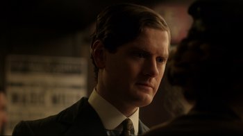 Movie still from “An Inspector Calls” (2015), directed by Raymond Pak-Ming Wong – A person wearing a suit and tie; Close Up shot, Over the shoulder angle