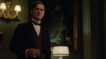 Movie still from “An Inspector Calls” (2015), directed by Raymond Pak-Ming Wong – A man in a suit holding a glass of wine; Medium shot, Low angle