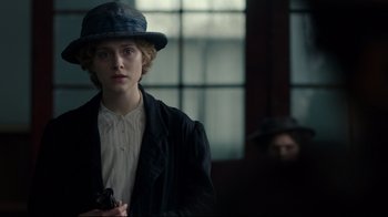 Movie still from “An Inspector Calls” (2015), directed by Raymond Pak-Ming Wong – A young man in a hat and a jacket holding a gun in front of a window; Medium shot, Over the shoulder angle